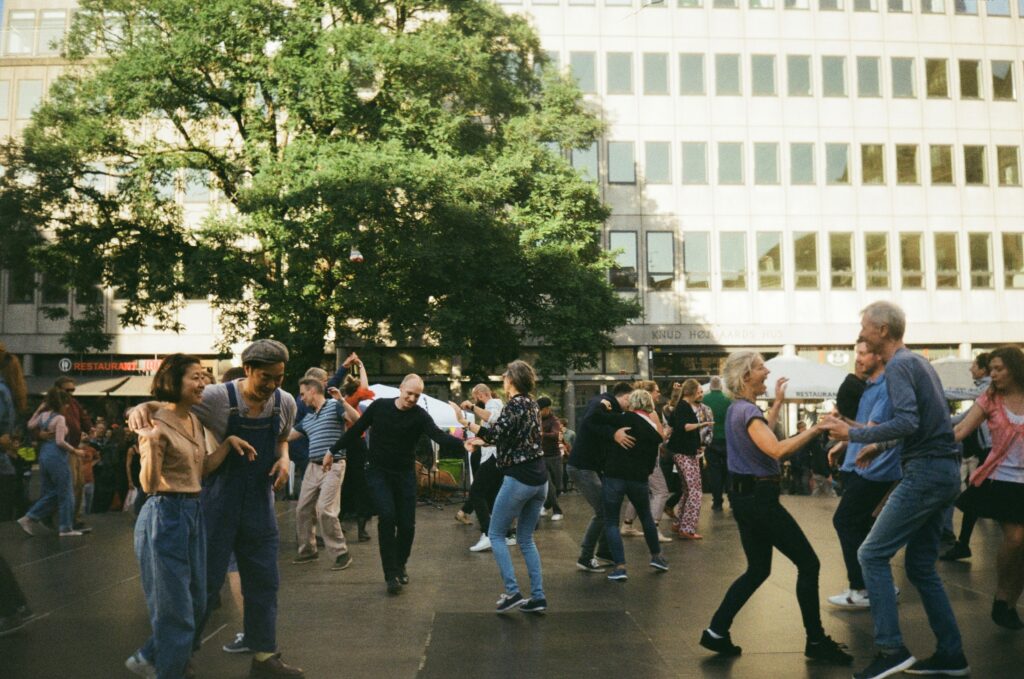 Happy people dancing together outdoors in a city square